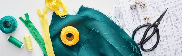 Tiro panorâmico de zíperes, tesouras, dedais, fios, bolas de fios de tricô, tecido e padrões de costura no fundo branco — Fotografia de Stock