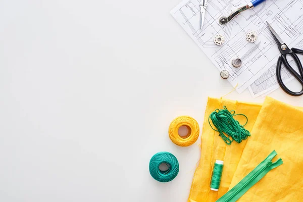 Top view of zipper, scissors, thimbles, threads, knitting yarn balls, fabric, tracing wheel, sewing patterns on white background — Stock Photo