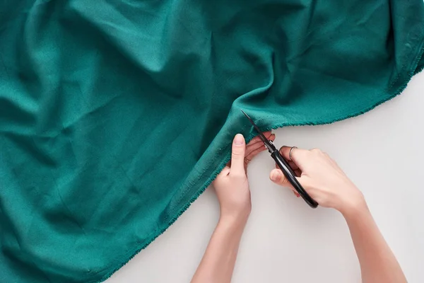 Top view of seamstress cutting colorful fabric with scissors on white background — Stock Photo