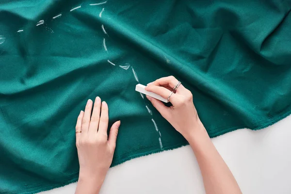 Vue du dessus du dessin de couturière sur tissu coloré avec craie sur fond blanc — Photo de stock