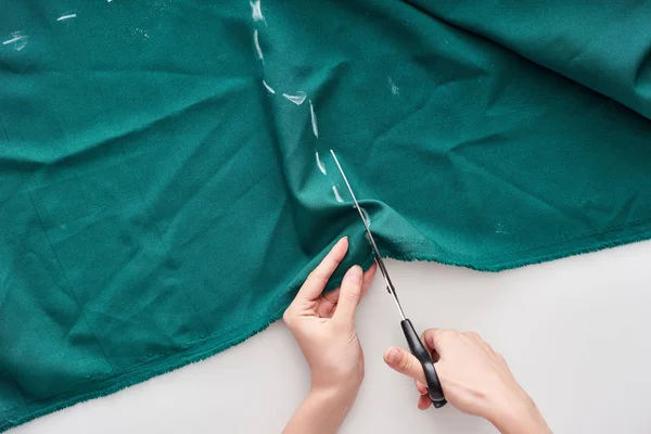 Top view of seamstress cutting colorful fabric with scissors on white background — Stock Photo