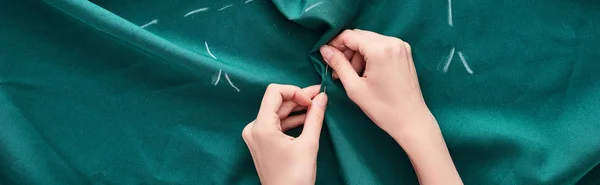 Panoramic shot of seamstress sewing colorful fabric with needle on white background — Stock Photo
