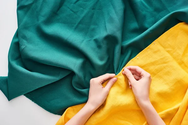 Top view of seamstress sewing colorful fabric with needle on white background — Stock Photo