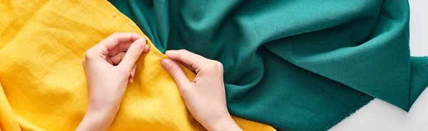 Panoramic shot of seamstress sewing colorful fabric with needle — Stock Photo