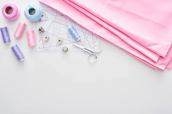 Ansicht von Stoff, Strickgarnbällchen, Schnittmuster, Scheren, Fingerhüte, Spulen und Fäden auf weißem Hintergrund — Stockfoto