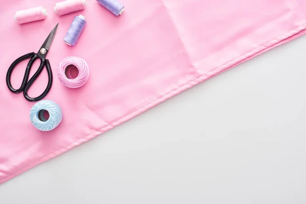 Top view of fabric, knitting yarn balls, scissors and threads on white background — Stock Photo