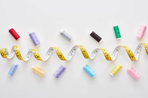 Top view of measuring tape and colorful threads on white background — Stock Photo