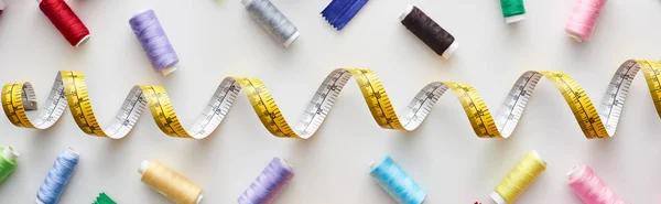 Top view of measuring tape, colorful threads on white background — Stock Photo