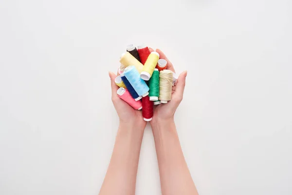 Vista recortada de la mujer sosteniendo hilos brillantes y coloridos sobre fondo blanco - foto de stock