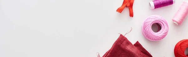 Panoramic shot of colorful threads, knitting yarn balls, fabric and zipper on white background — Stock Photo