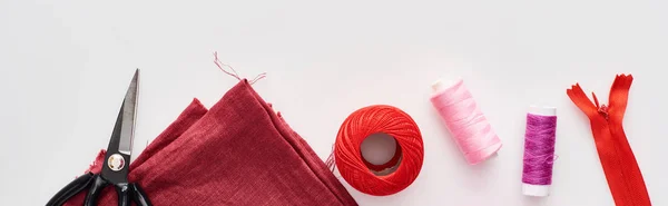 Panoramic shot of colorful threads, knitting yarn ball, fabric, scissors and zipper on white background — Stock Photo