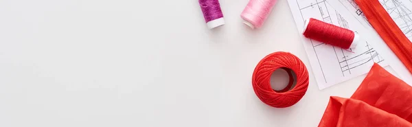 Panoramic shot of colorful threads, knitting yarn ball, fabric, sewing patterns and zipper on white background — Stock Photo