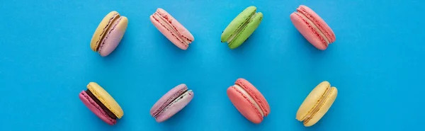 Flat lay with sweet multicolored delicious French macaroons on blue bright background, panoramic shot — Stock Photo