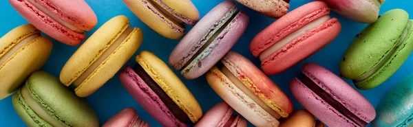 Top view of colorful assorted French macaroons on blue bright background, panoramic shot — Stock Photo