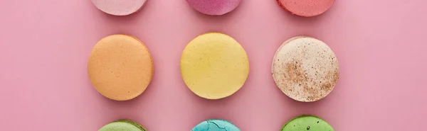 Plat étendu avec de délicieux macarons français multicolores sur fond rose, vue panoramique — Photo de stock