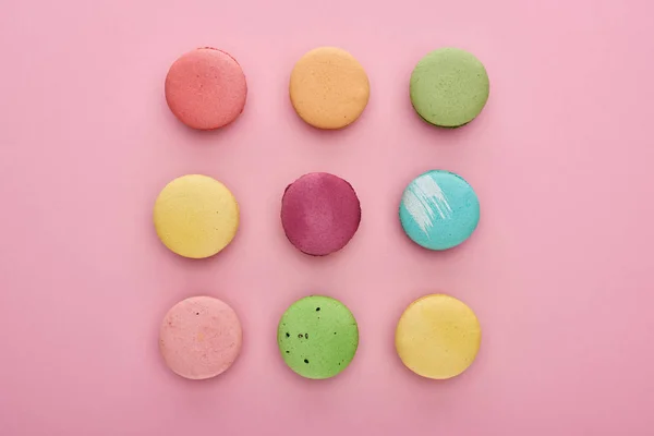 Flat lay com deliciosos macaroons franceses no fundo rosa — Fotografia de Stock