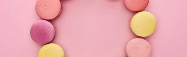 Marco de macarrones franceses deliciosos multicolores sobre fondo rosa, plano panorámico - foto de stock