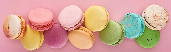 Top view of fresh delicious French macaroons on pink background, panoramic shot — Stock Photo