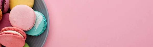 Vista ravvicinata di deliziosi macaron francesi multicolori su piatto su sfondo rosa, scatto panoramico — Foto stock