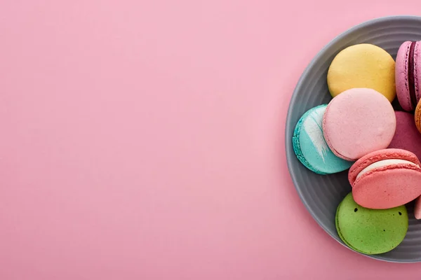 Plate with multicolored delicious French macaroons on pink background with copy space — Stock Photo