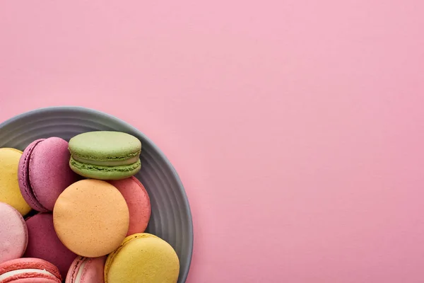 Vista de cerca de la placa con macarrones franceses deliciosos multicolores sobre fondo rosa - foto de stock