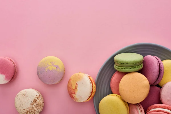 Plate with multicolored fresh delicious French macaroons on pink background — Stock Photo