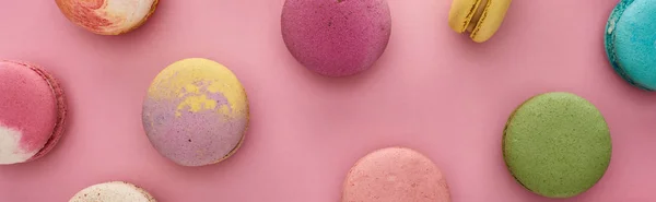 Pattern of multicolored delicious French macaroons on pink background, panoramic shot — Stock Photo
