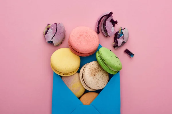 Vista superior de macaroons franceses deliciosos multicoloridos em envelope postal azul no fundo rosa — Fotografia de Stock