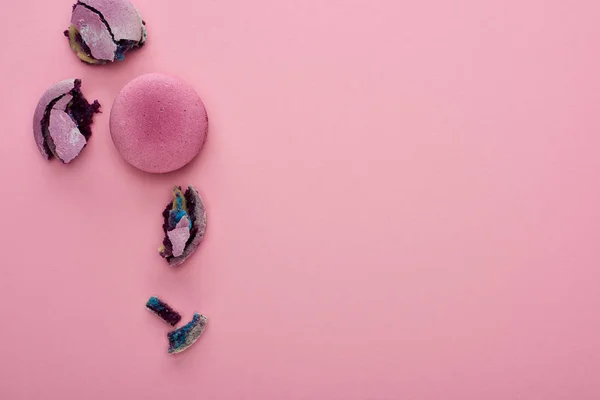 Top view of smashed and whole delicious purple French macaroons on pink background with copy space — Stock Photo