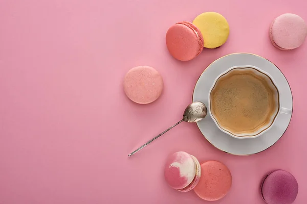 Top view of delicious French macaroons near coffee on pink background with copy space — Stock Photo