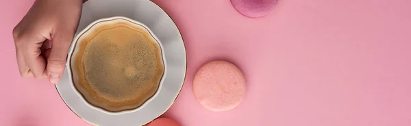 Vista cortada de mulher bebendo café com deliciosos macaroons franceses no fundo rosa, tiro panorâmico — Fotografia de Stock