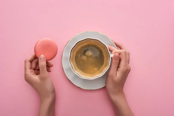 Teilansicht einer Frau, die Kaffee mit köstlichen französischen Makronen auf rosa Hintergrund trinkt — Stockfoto