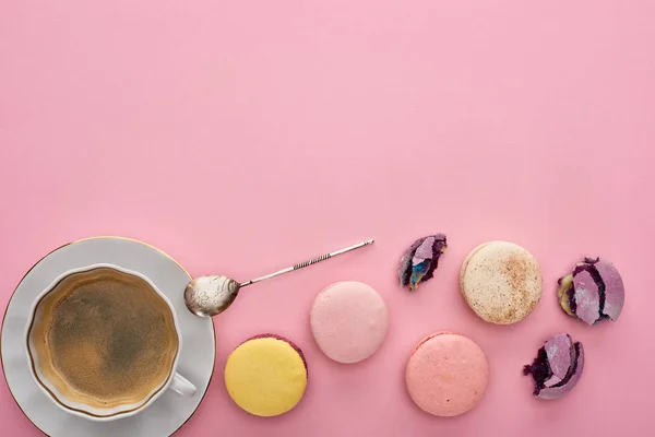 Vue de dessus de délicieux macarons français près du café avec cuillère en argent sur fond rose avec espace de copie — Photo de stock