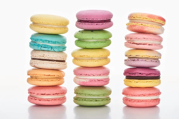 Tres filas de dulces macarrones franceses multicolores de diferentes sabores sobre fondo blanco - foto de stock