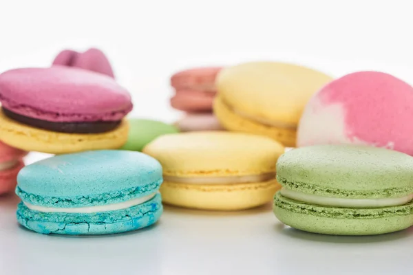 Vista de cerca de macarrones franceses de colores dulces de diferentes sabores sobre fondo blanco - foto de stock