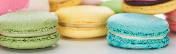 Vista de perto de macaroons franceses coloridos doces de sabores diferentes no fundo branco, tiro panorâmico — Fotografia de Stock