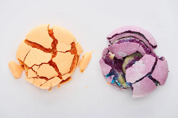 Top view of delicious orange and purple smashed French macaroons isolated on white — Stock Photo