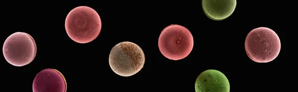 Top view of delicious French macaroons of different flavors isolated on black, panoramic shot — Stock Photo