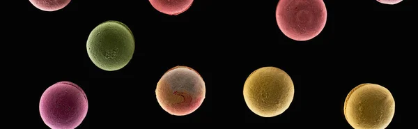 Top view of colorful French macaroons of different flavors isolated on black, panoramic shot — Stock Photo