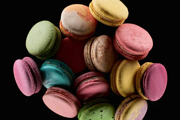 Mucchio di deliziosi macaron francesi colorati di diversi sapori isolati su nero — Foto stock