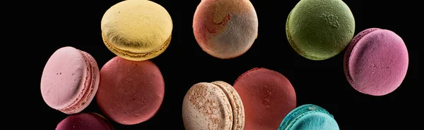 Haufen köstlicher farbenfroher französischer Makronen unterschiedlicher Geschmacksrichtungen isoliert auf schwarzem, panoramischem Foto — Stockfoto