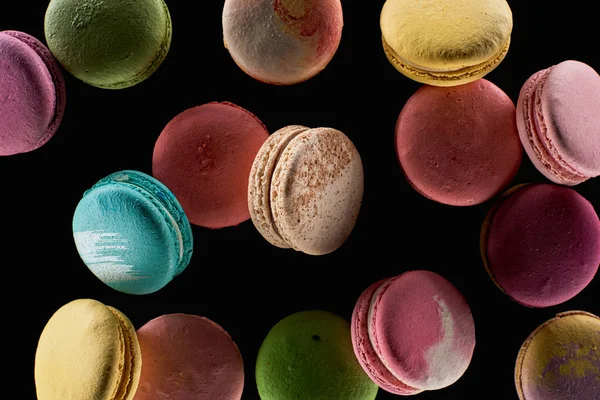 Vista superior de macaroons franceses coloridos deliciosos espalhados de sabores diferentes isolados no preto — Fotografia de Stock