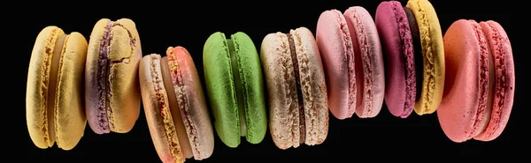 Vista superior de saborosos macaroons franceses coloridos de diferentes sabores isolados em preto, tiro panorâmico — Fotografia de Stock