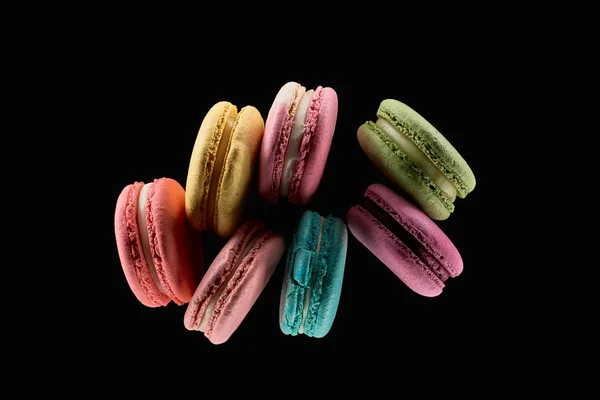 Vue de dessus de délicieux macarons français colorés de différentes saveurs isolés sur noir — Photo de stock