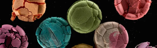 Top view of smashed delicious French macaroons of different flavors isolated on black, panoramic shot — Stock Photo