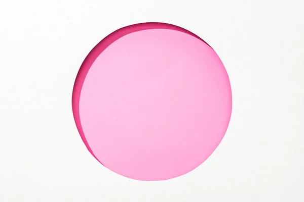 Cut out round hole in white paper on pink colorful background — Stock Photo