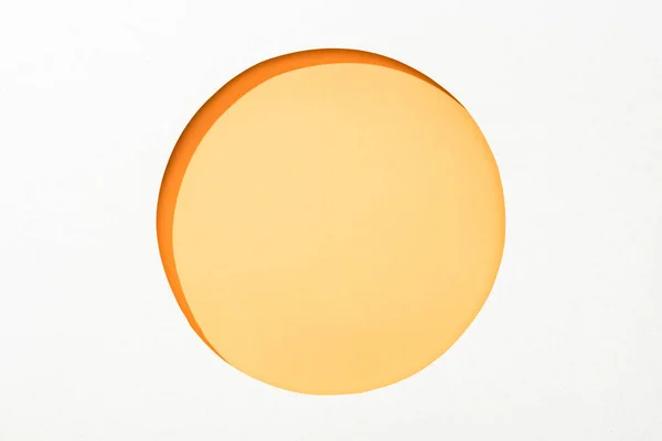 Cut out round hole in white paper on yellow colorful background — Stock Photo