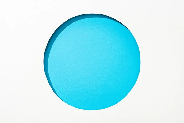 Découper trou rond en papier blanc sur fond bleu brillant coloré — Photo de stock