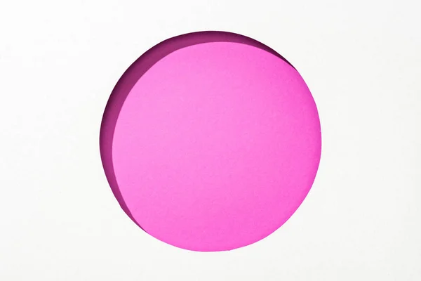 Recortar buraco redondo em papel branco sobre fundo colorido rosa brilhante — Fotografia de Stock