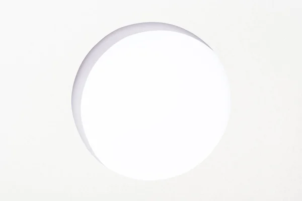 Cut out round hole in white paper on white background — Stock Photo